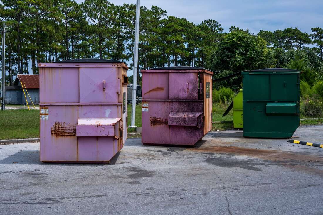 Three large dumpsters on pavement